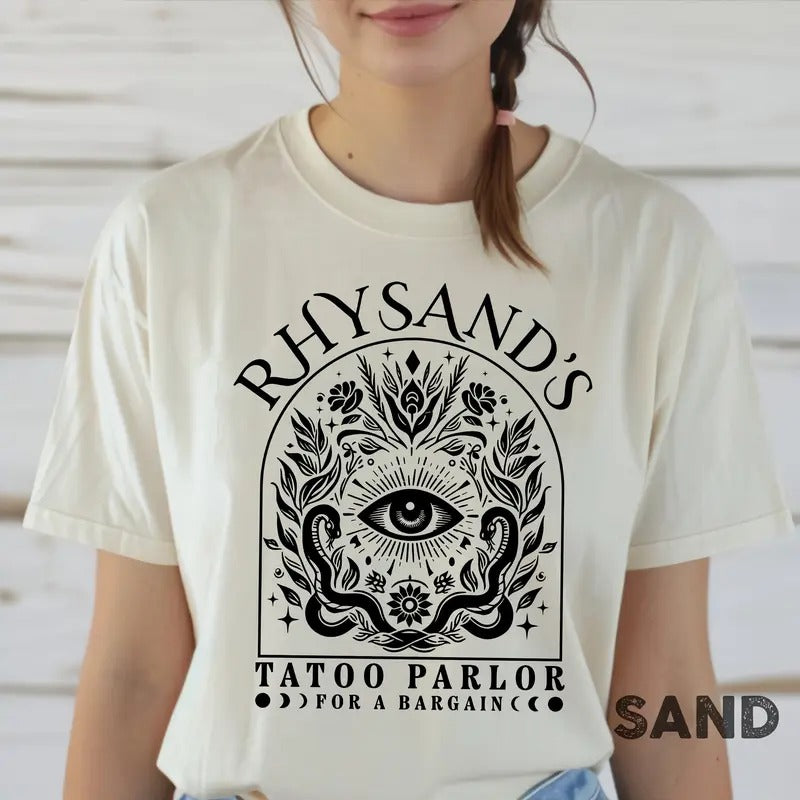 is a mAcotar Velaris Rhysand's Tattoo Parlor T-shirt featuring Feyre and Rhysandust-have for fans of the novel series. Perfect for book lovers, this tee celebrates the Night Court with style.