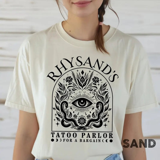 is a mAcotar Velaris Rhysand's Tattoo Parlor T-shirt featuring Feyre and Rhysandust-have for fans of the novel series. Perfect for book lovers, this tee celebrates the Night Court with style.